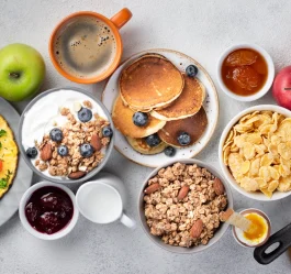 صبحانه سالم و متعادل با تخم‌مرغ، نان تست، اسموتی و میوه‌ها روی میز چوبی